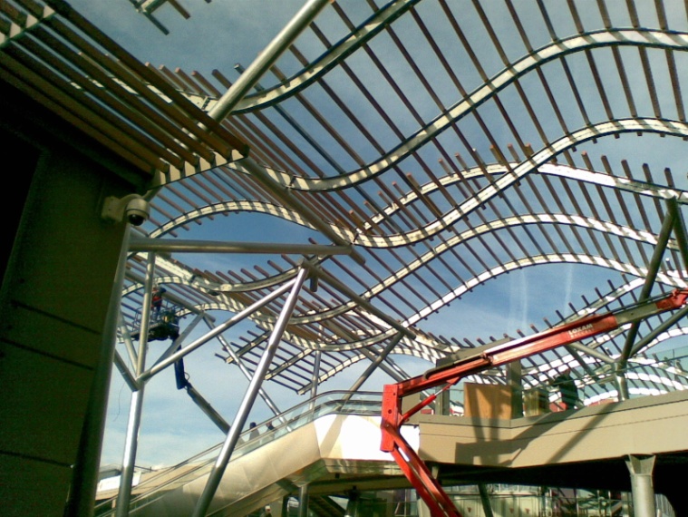 Structure en acier à formes ondulées en cours de montage sur un bâtiment contemporain.