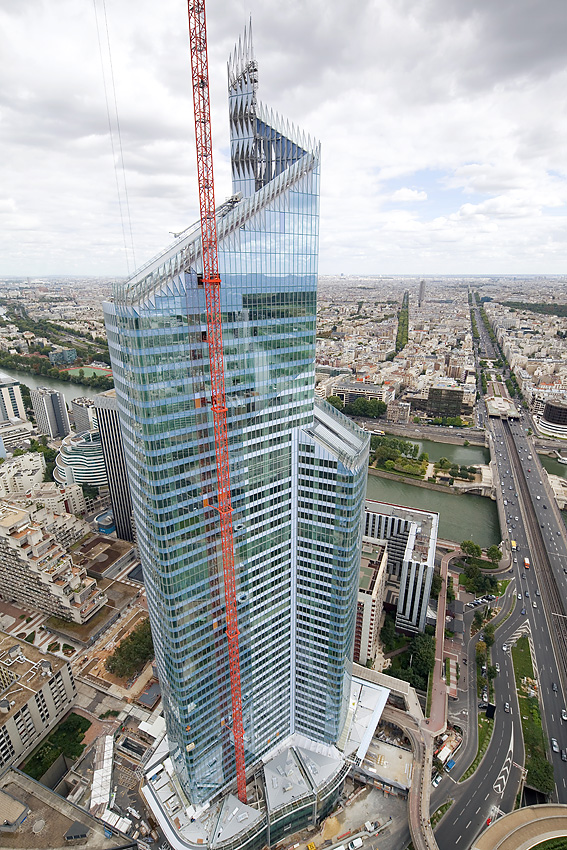 Vue aérienne de la tour First à Paris avec une grue en façade pendant le chantier.